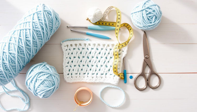 Yarn, crochet hooks and other materials needed for the crochet beach cover up free pattern laid out on a wooden surface